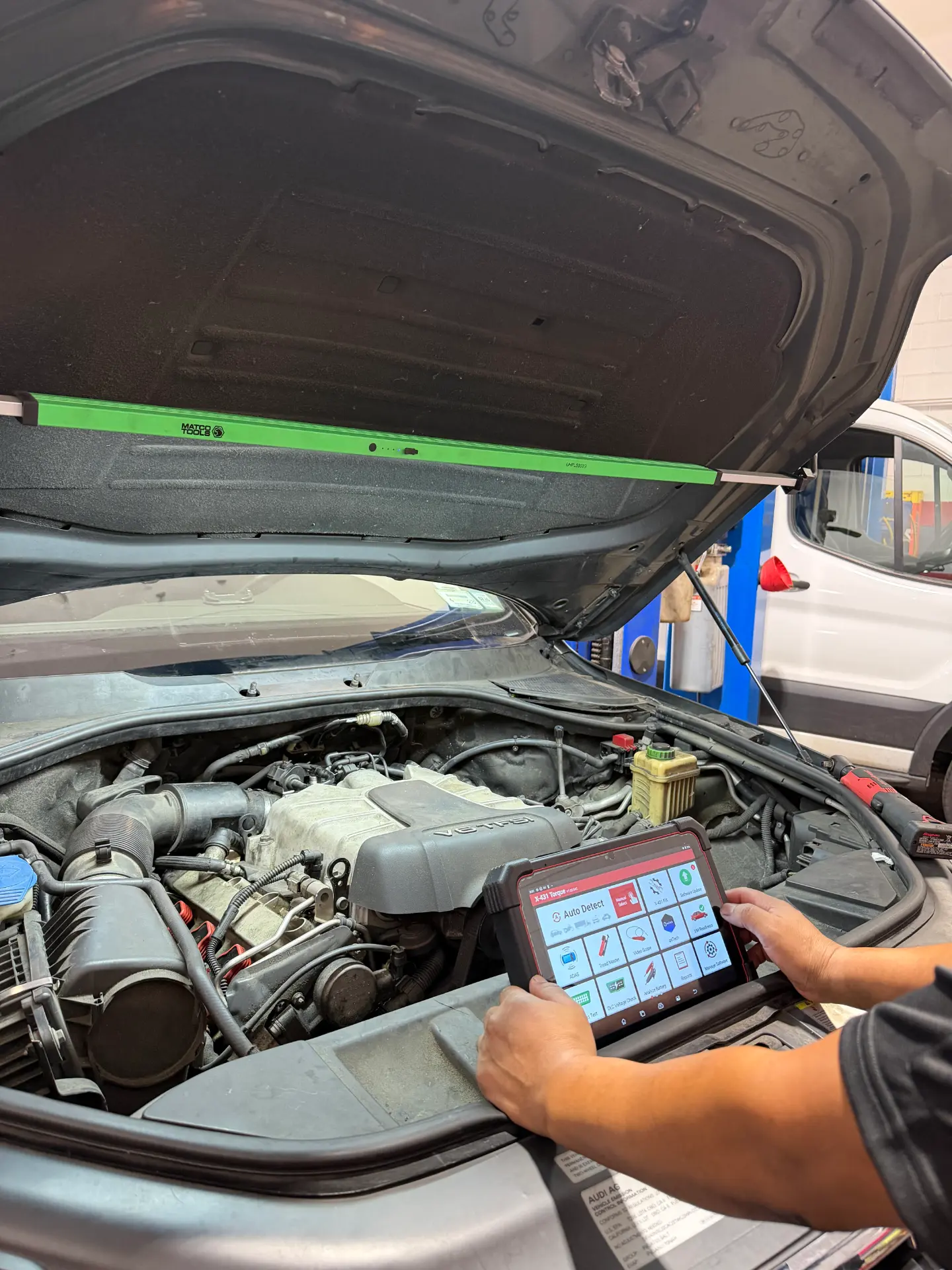 Technician running a diagnostic scan on an Audi V6 TFSI engine with the hood raised at the Wappingers Falls shop