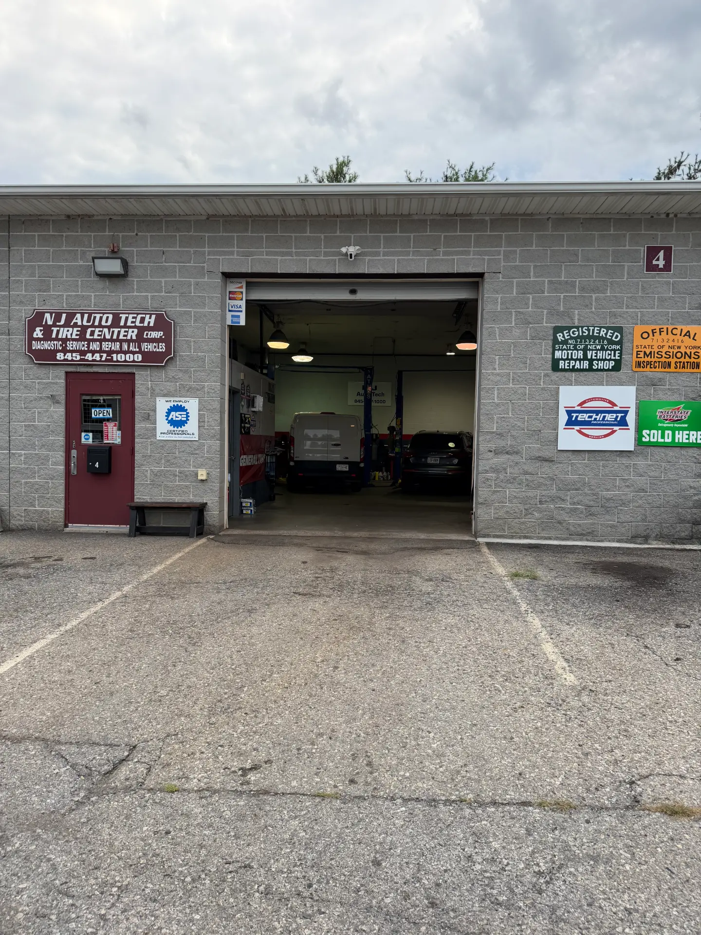 NJ Auto Tech Automotive Specialist storefront entrance with New York registered motor vehicle repair shop and official emissions inspection station signs in Wappingers Falls, NY