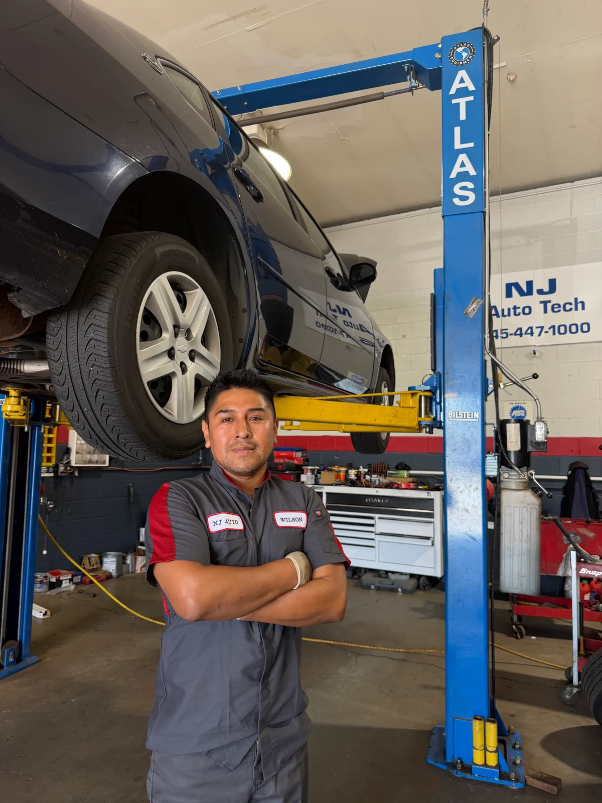 Owner-operator Wilson Sacasari in front of a vehicle on the lift at the Wappingers Falls auto repair shop