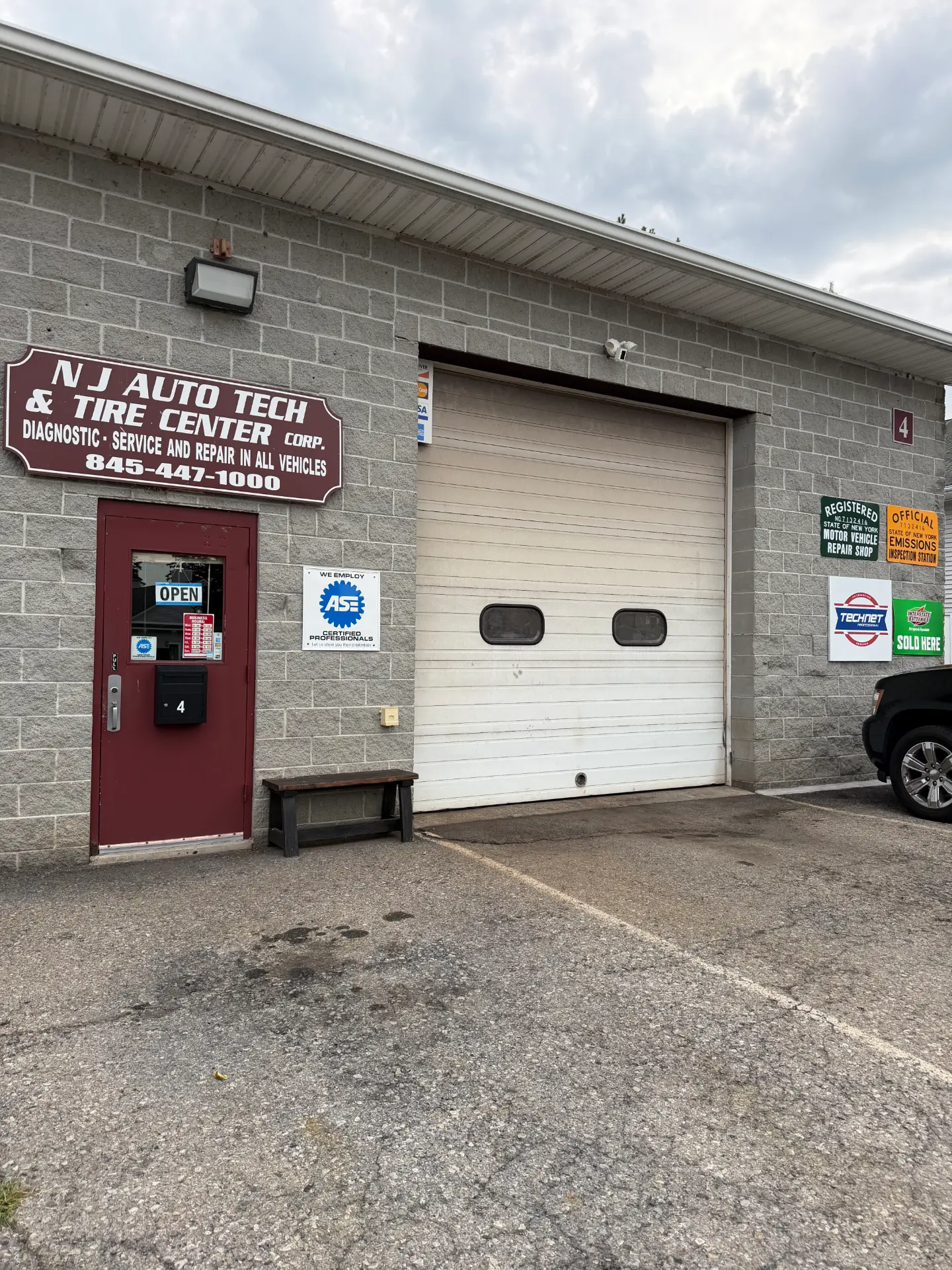 Exterior of the NJ Auto Tech Automotive Specialist building showing the shop sign, ASE certified professionals decal and closed service bay door