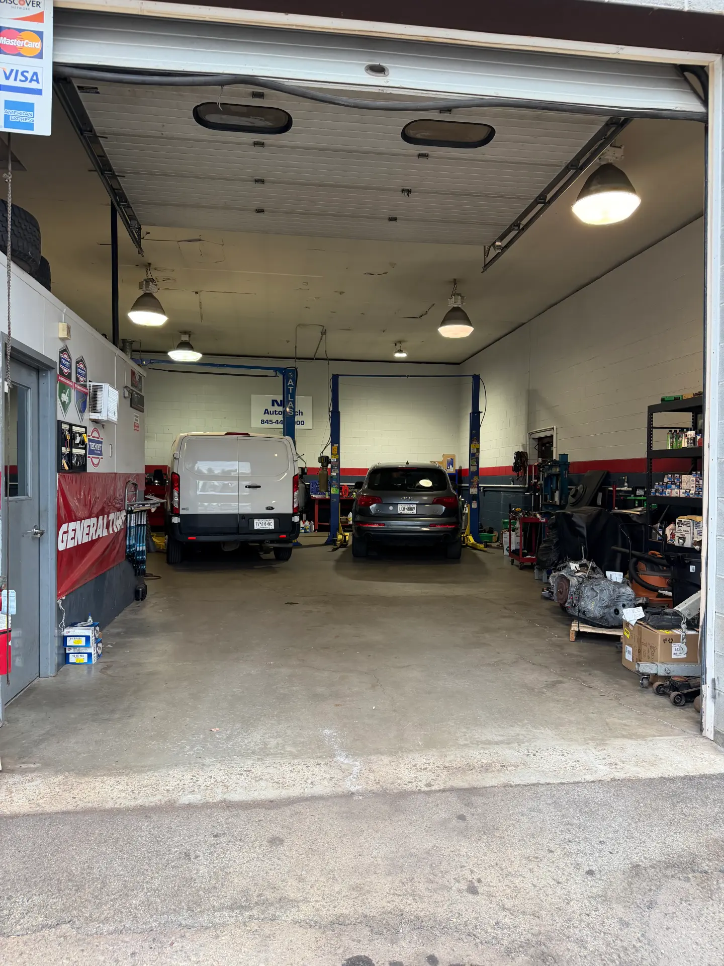 Inside view of the NJ Auto Tech service bays with a cargo van and an Audi SUV on the lifts in Wappingers Falls, NY