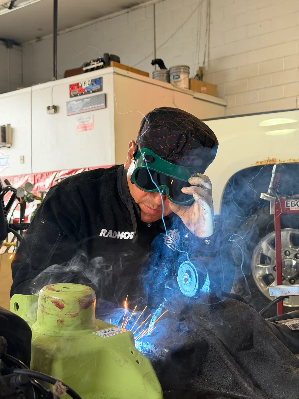 Automotive welding and fabrication work being performed with protective goggles in the shop