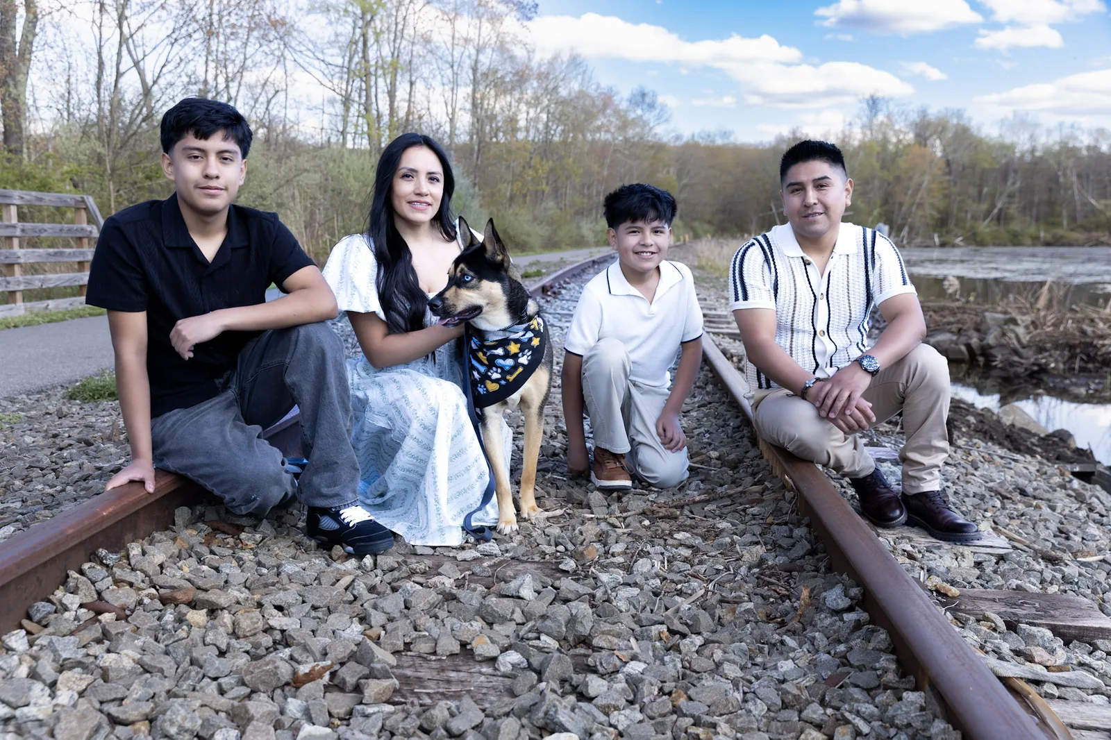 The Sacasari family with their dog sitting on railroad tracks in the Hudson Valley